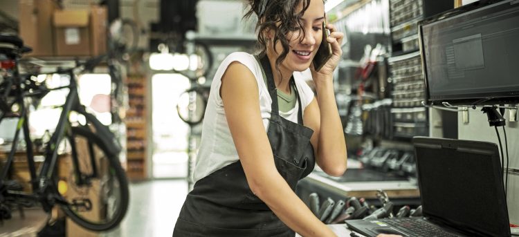 Beautiful young female bicycle mechanic working on a customer bicycle