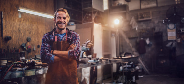 Portrait of smiling mechanic standing in garage workshop with professional equipment